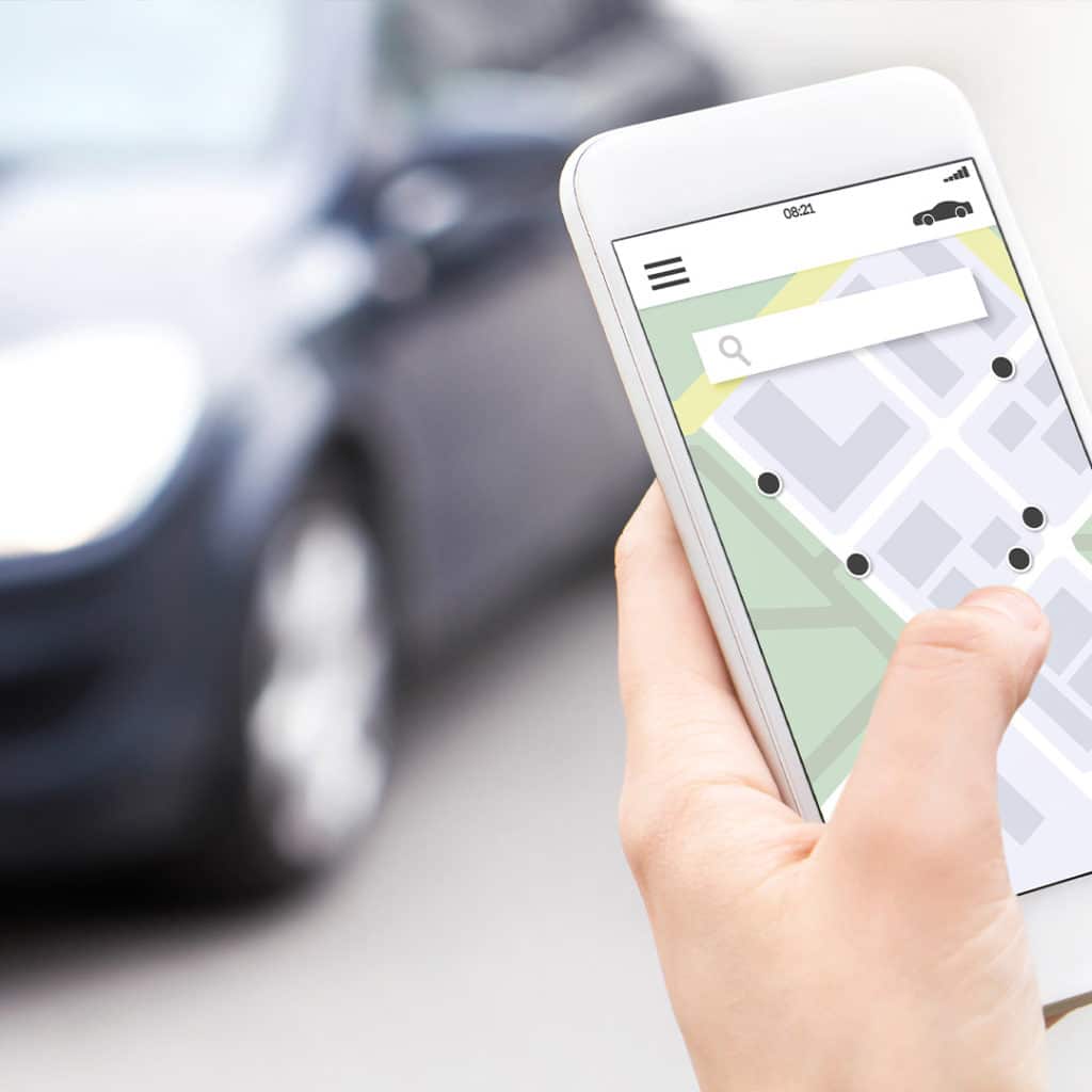 Woman holding phone displaying the whereabouts of car in car sharing app